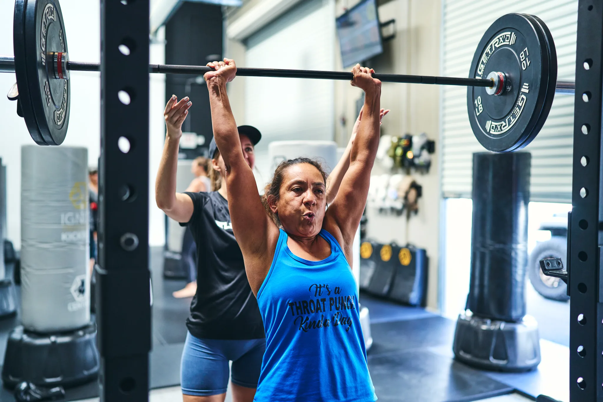 Personal training at Evolve Kickbox in Las Vegas — a member pressing a barbell overhead with a strength coach spotting